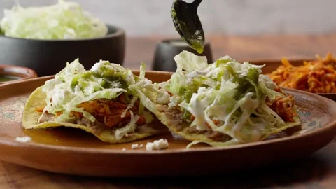 Mexican toasts, adding spicy green sauce to a couple of tostadas with chicken Stock Footage 281392942