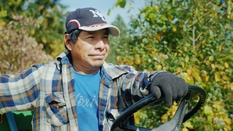 A Mexican worker is sitting behind the wheel of a small tractor. Stock Footage
