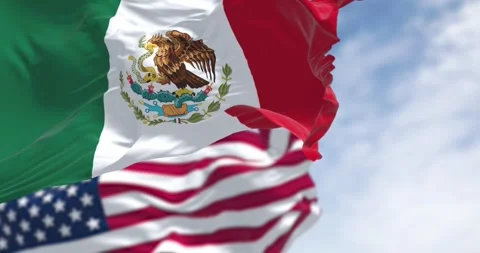 Mexico and US national flags waving on a clear day Stock Footage 302289112