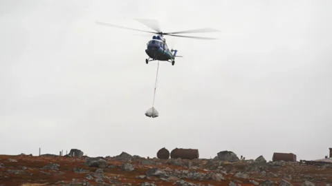 Mi-8 helicopter lands with cargo-white bags swinging under it, hanging on ropes Stock Footage 137758111