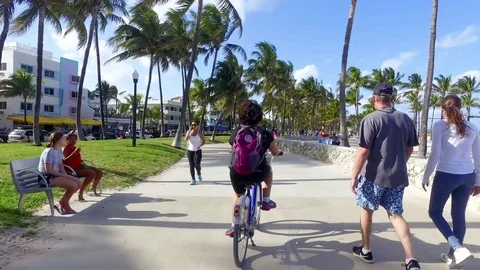 Miami Beach Florida USA Riding a Bike Down Lummus Park Boardwalk Stock Footage