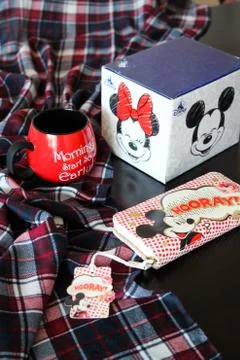 Mickey mouse tea cup and wallet stands on a black table Stock Photos