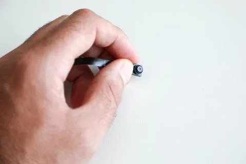 A micro camera is held between the fingers of one hand Stock Photos
