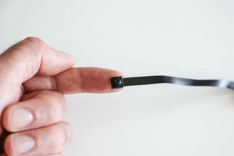 A micro camera is held between the fingers of one hand Stock Photos