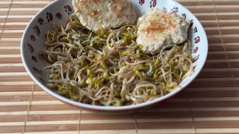 Micro-greenery. Green white sprouted mung beans with two fried cutlet cooking in Stock Footage 275751951