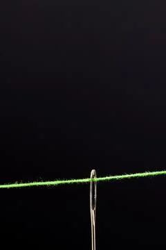 Micro of needle with green thread and copy space on black background 写真素材