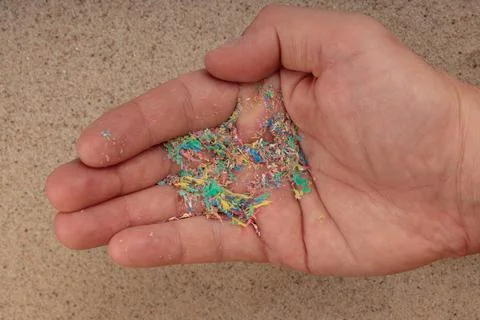 Micro plastic on the palm of your hand, top view of the beach. An environment Foto stock