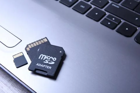 Micro SD memory card adapter on grey laptop keyboard on the wooden table. clo Stock Photos