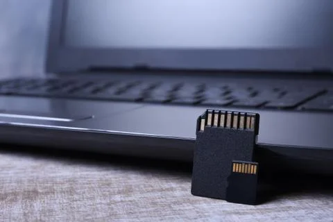 Micro SD memory card adapter on laptop background on the wooden table. close Stock Photos