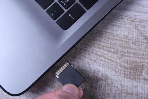 Micro SD memory card adapter on grey laptop keyboard on the wooden table. clo Stock Photos