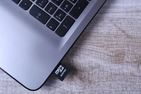 Micro SD memory card adapter on grey laptop keyboard on the wooden table. clo Stock Photos