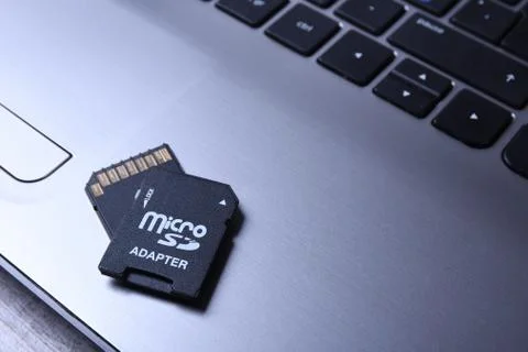 Micro SD memory card adapter on grey laptop keyboard on the wooden table. clo Stock Photos