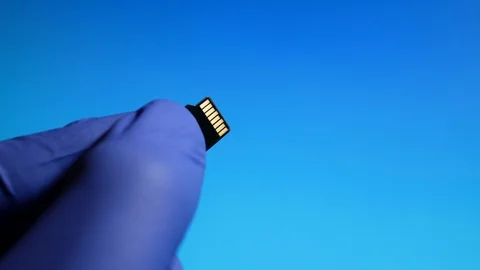 Micro SD memory card in hand close-up on blue background Stock Footage 129981901