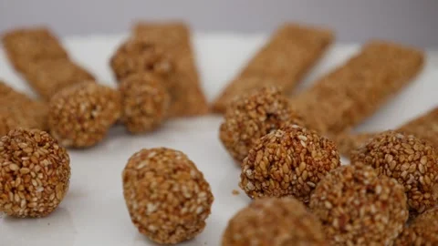 Micro shot of dropping sesame seeds ladoo over a plate Stock-Footage 147694735