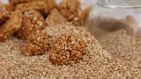 Micro shot of dropping sesame seeds over a ladoo isolated on white background Vídeo Stock 147695422