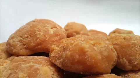 Micro shot of Jaggery or Gur pieces rotating on white background. sugar cane Video stock 284107255
