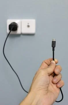 Micro usb wire in hand against the background of the power supply Stock Photos