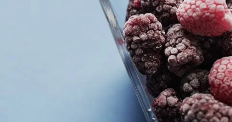 Micro video of close up of raspberries in glass bowl with copy space on blue Stock Footage 331246515