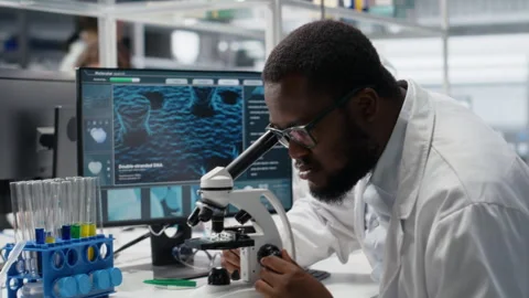 Microbiologist in lab inspects slide using optical device, analyzing on PC Stock Footage 320145429