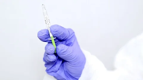 Microbiologist or medical worker with blue surgical gloves giving the vaccine Stock Footage 128382383