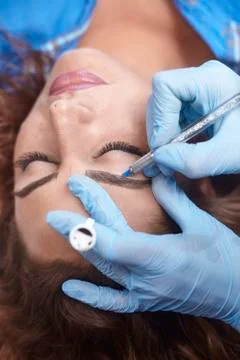 Microblading close-up, hands adding pigment to eyebrows. 스톡 사진