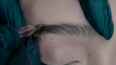 A microblading eyebrow master makes a color at the edge of the eyebrow Stock Footage 223155205