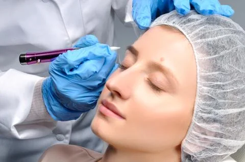 Microblading eyebrows. Cosmetologist making permanent makeup. Attractive woma Фото