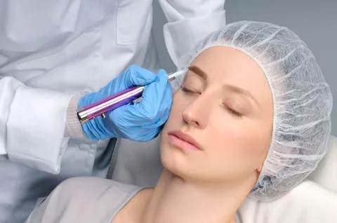 Microblading eyebrows. Cosmetologist making permanent makeup. Attractive woma Fotos de archivo