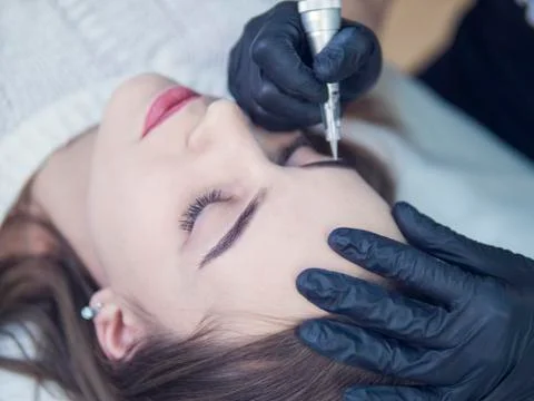 Microblading eyebrows workflow in a beauty salon. Light brown girl do eyebrows Stock Photos