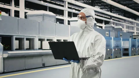 Microchip factory specialist tests silicon wafer batches with laptop Stock Footage 333393776