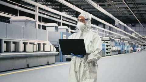 Microchip factory specialist tests silicon wafer batches with laptop Stock Footage 333395440
