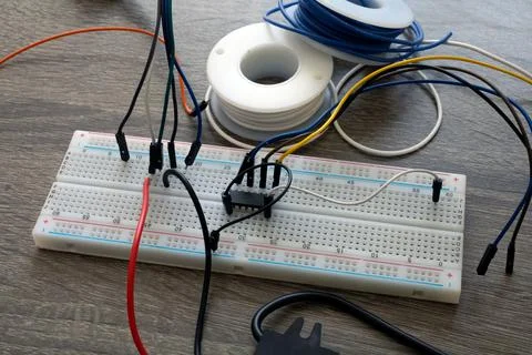 A microchip with wires on a breadboard for electrical engineering on a wooden Stock Photos