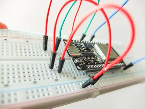 Microcontroller board with connected colorful jumper wires on electronic brea Photos