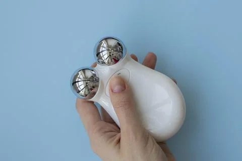 Microcurrent device in the hand on a blue background. Modern cosmetic treatme Stock Photos