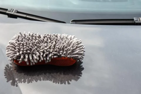 Microfiber sponge lies on the dirty hood of the car Stock Photos