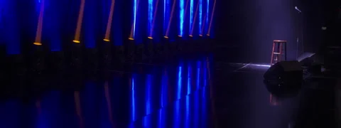 Microphone and chair on empty stage illuminated by spotlight beam in smoke Stock Footage 250006897