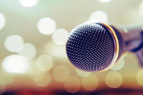 Microphone in the background with bright lights on the singing contest stage. Stock Photos