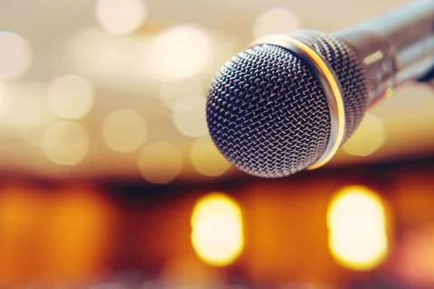 Microphone in the background with bright lights on the singing contest stage. Stock Photos