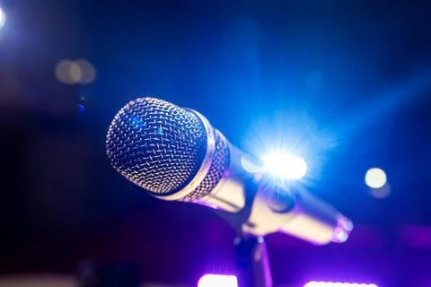 The microphone is in the blue rays of the spotlights on the stage. The concep 库存照片