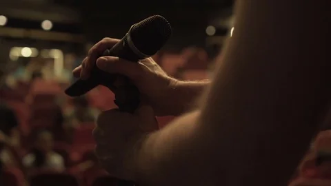 Microphone checks on stage, red chairs and audience in theater Stock Footage 76367635