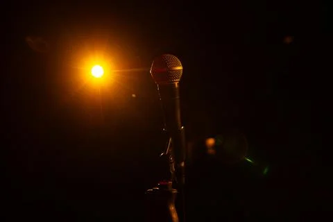 Microphone on the empty stage with spotlights Stock Photos