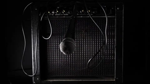 Microphone falling in slow motion swinging down hitting amplifiers straight on Stock Footage 204959936