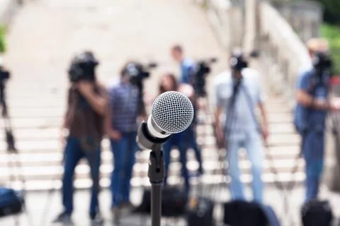 Microphone in focus against blurred camera operators and journalists at news Stock Photos