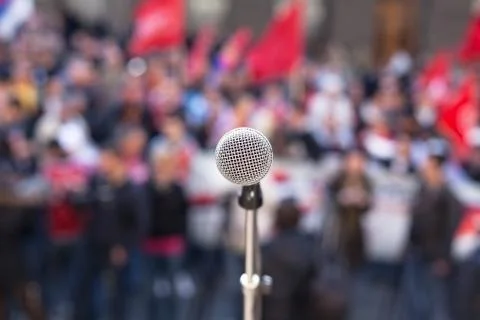 Microphone in focus against unrecognizable crowd of people Stock Photos