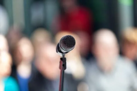 Microphone in focus, blurred audience in background Stock Photos