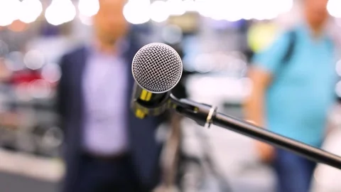Microphone in focus, blurred unrecognizable people waiting for media event Video stock 255296897