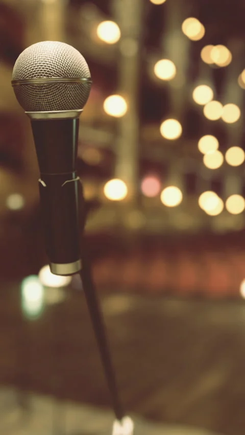 Microphone in focus on stage with blurred audience in background Stock Footage 329679418