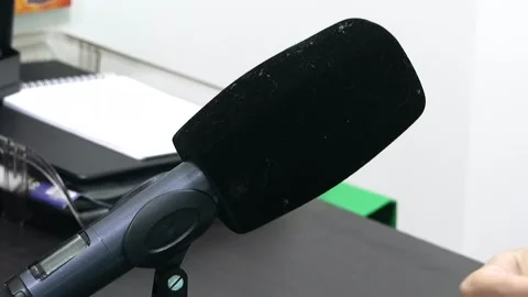 A microphone with a large black windscreen stands on a table Stock Footage 324766479