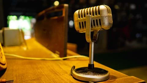 The microphone is located on a wooden table in an old music practice room. 스톡 사진
