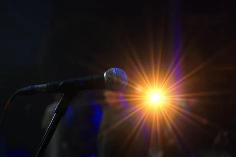A microphone is pointed at a bright light. The microphone is black and silv.. Stock Photos